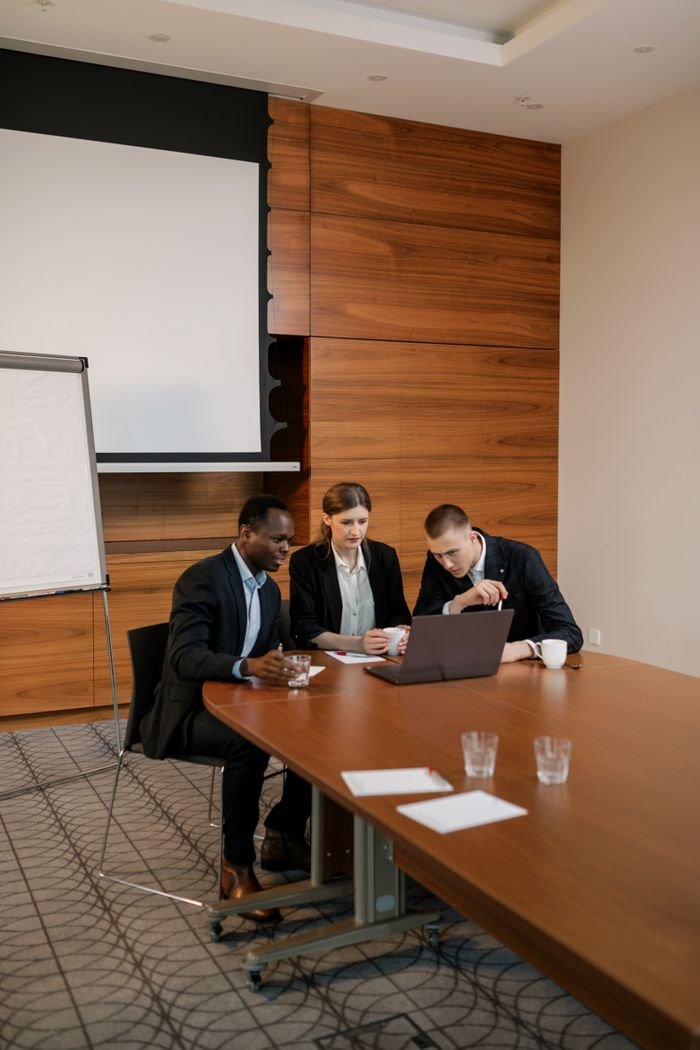 Three professionals reviewing a financing deal at a boardroom table