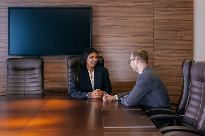 Two executives in discussion in a dark-wood boardroom