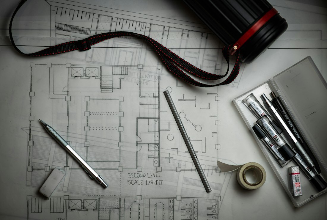 An architectural blueprint laid out with drafting pencils, a ruler, and drawing tools