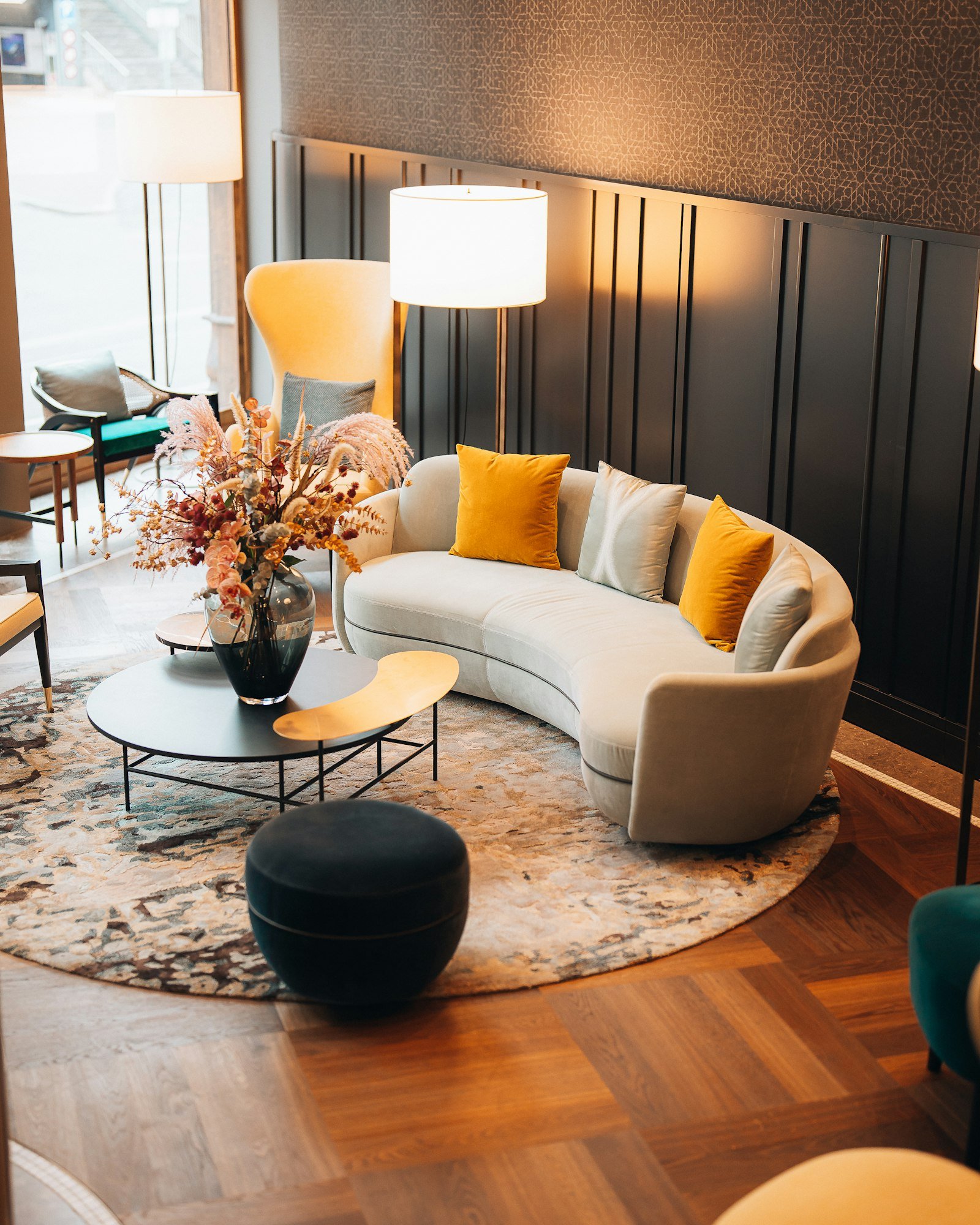 A modern community lounge with a curved cream sofa and warm lighting