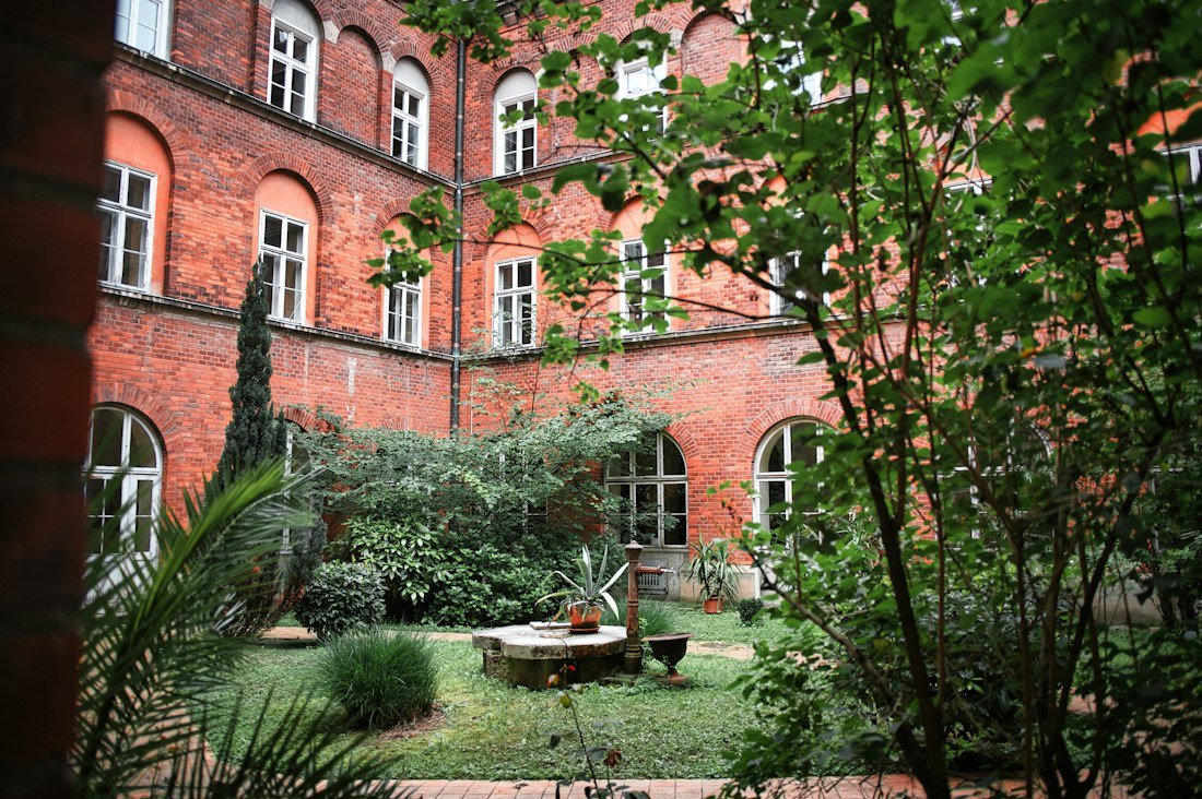 A red brick building around a leafy courtyard garden