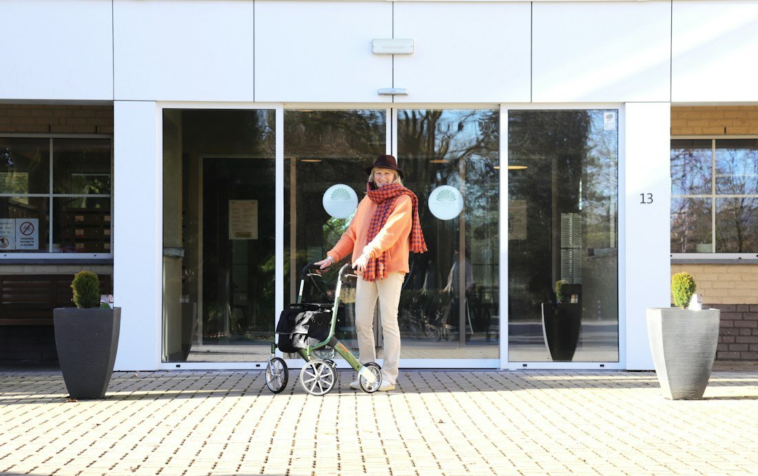 A resident with a walker entering a community's front entrance, with care continuing uninterrupted