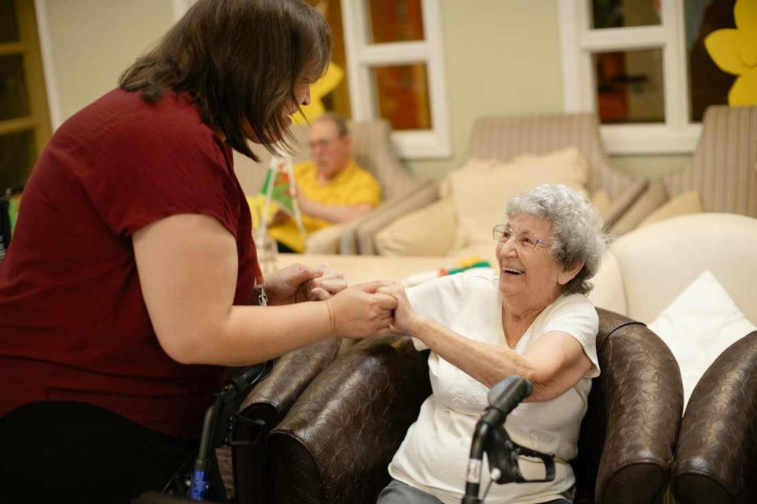 A caregiver helping a resident with her walker