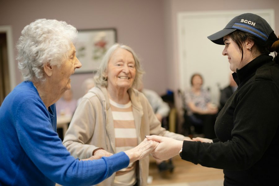 A caregiver holding hands with two residents, smiling together