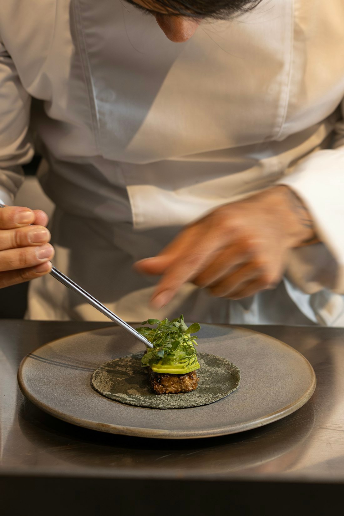 A chef carefully plating a meal, run to one standard