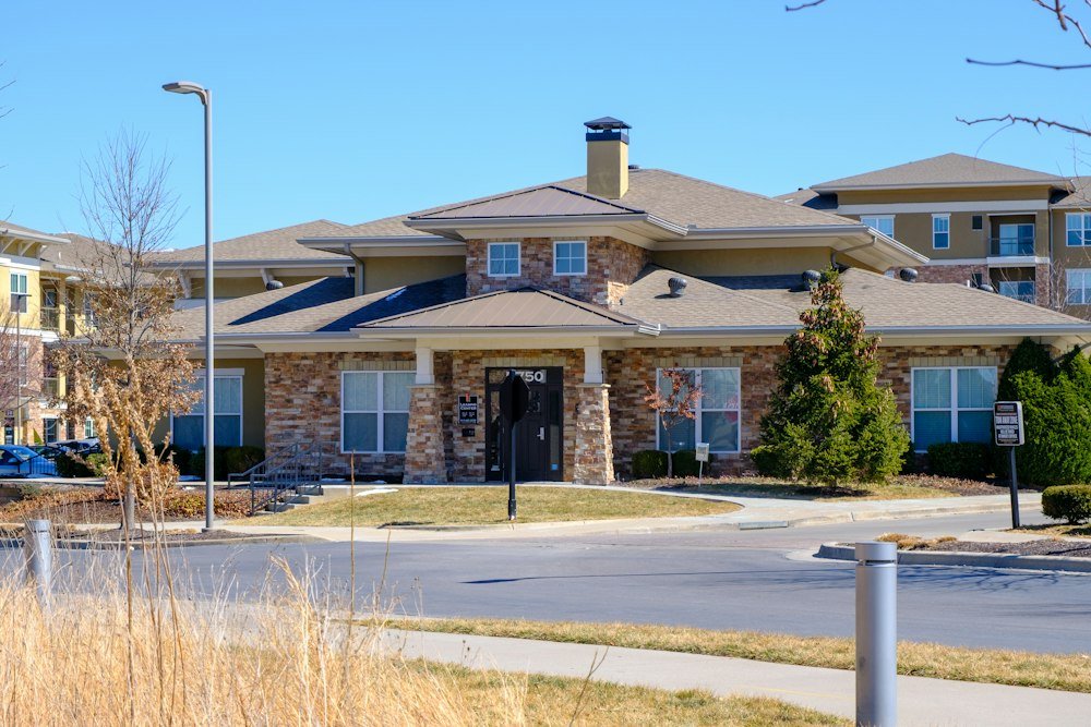 A modern senior living community exterior with stone and stucco architecture