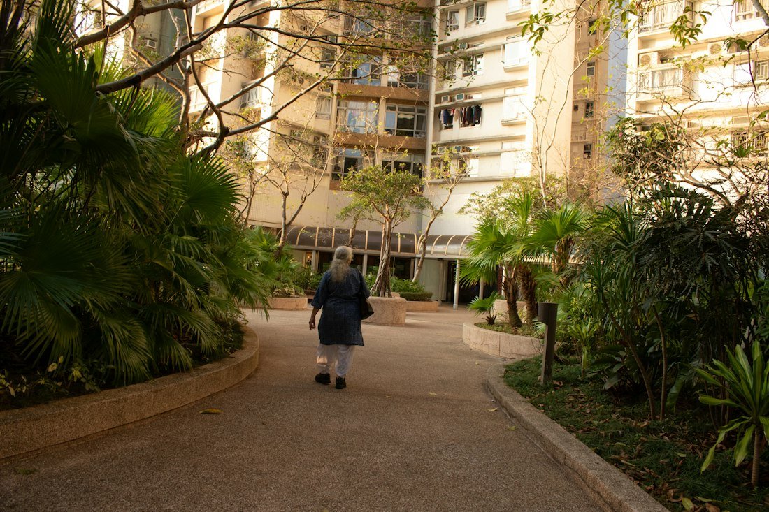 A resident walking along a paved path through a landscaped community courtyard
